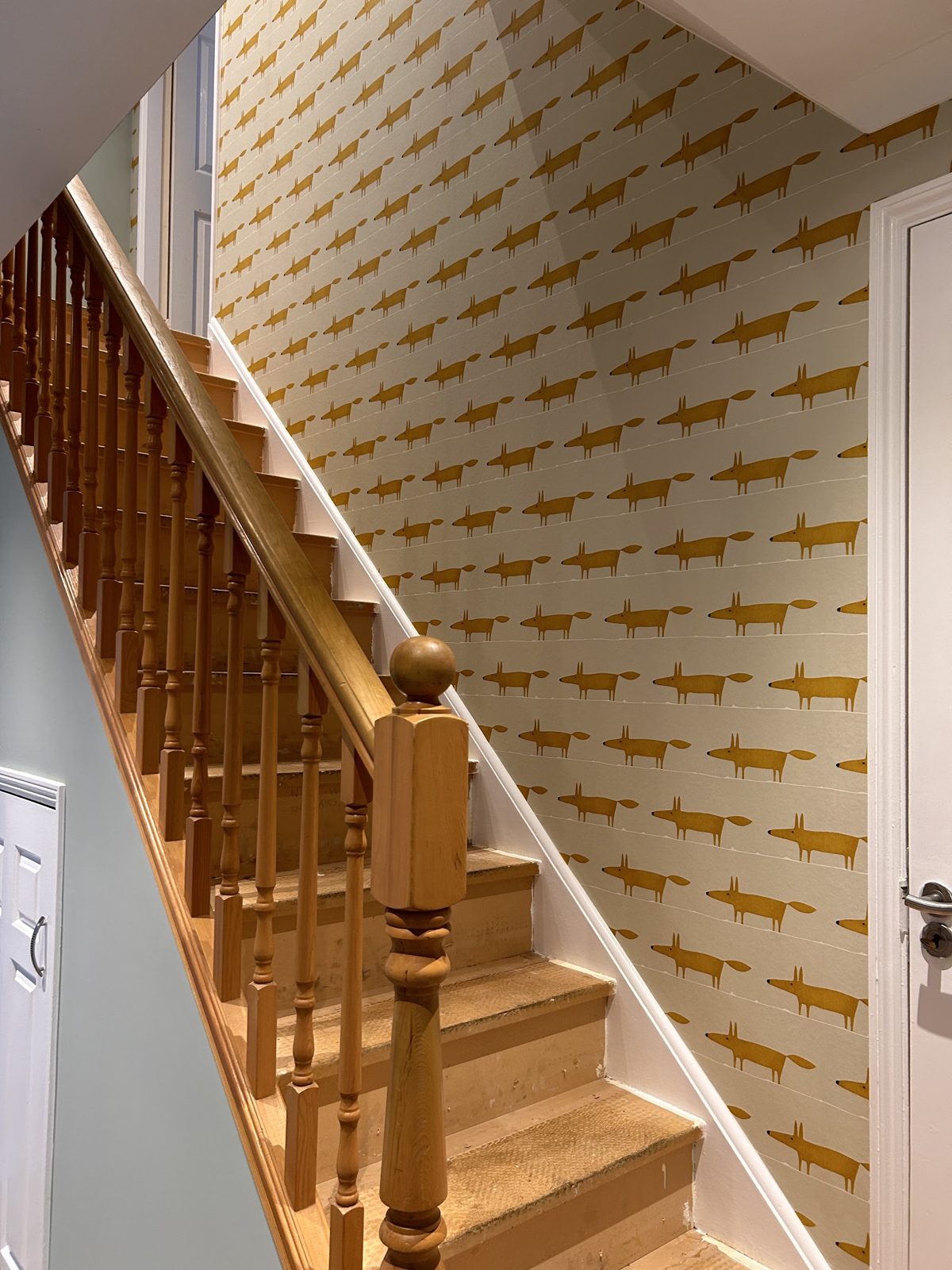 Staircase rising to a landing papered in fox wallpaper