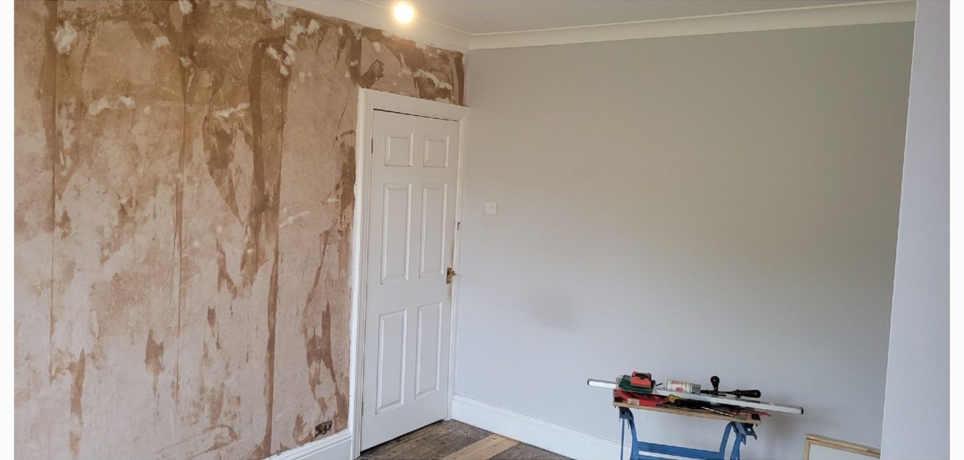 The same living room before: bare patched plaster wall